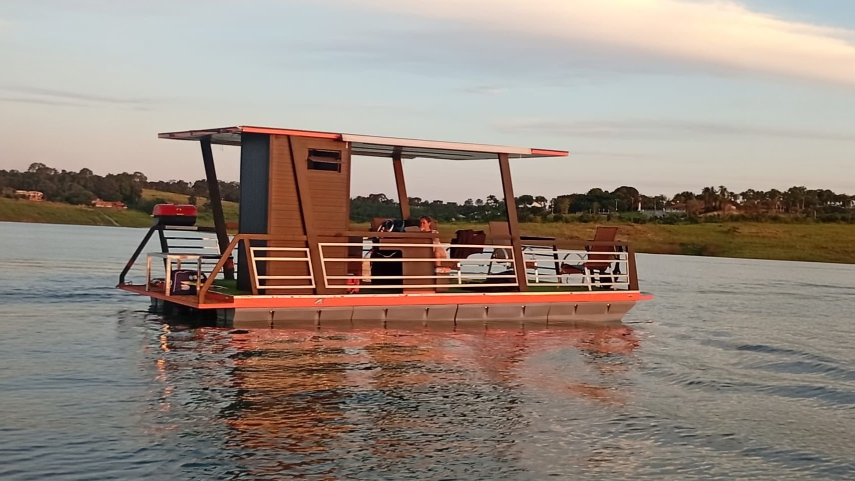 Casa flutuante montada sobre flutuadores Korreto numa represa ao fim da tarde